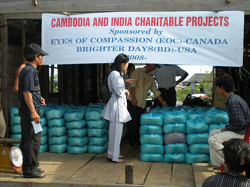 Volunteers with bundled supplies under a Cambodia and India charitable projects banner