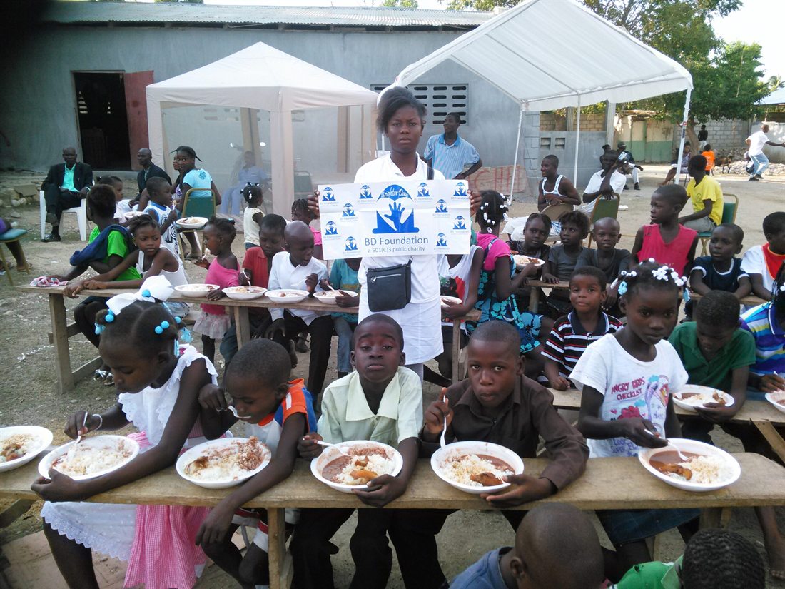 Children sharing a meal at BD Foundation tables during a mission trip in Haiti