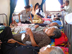 Patients resting on beds as caregivers attend to them in a relief medical clinic