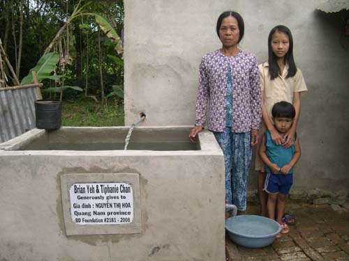 A family beside a BD Foundation water tank and tap built for their rural village